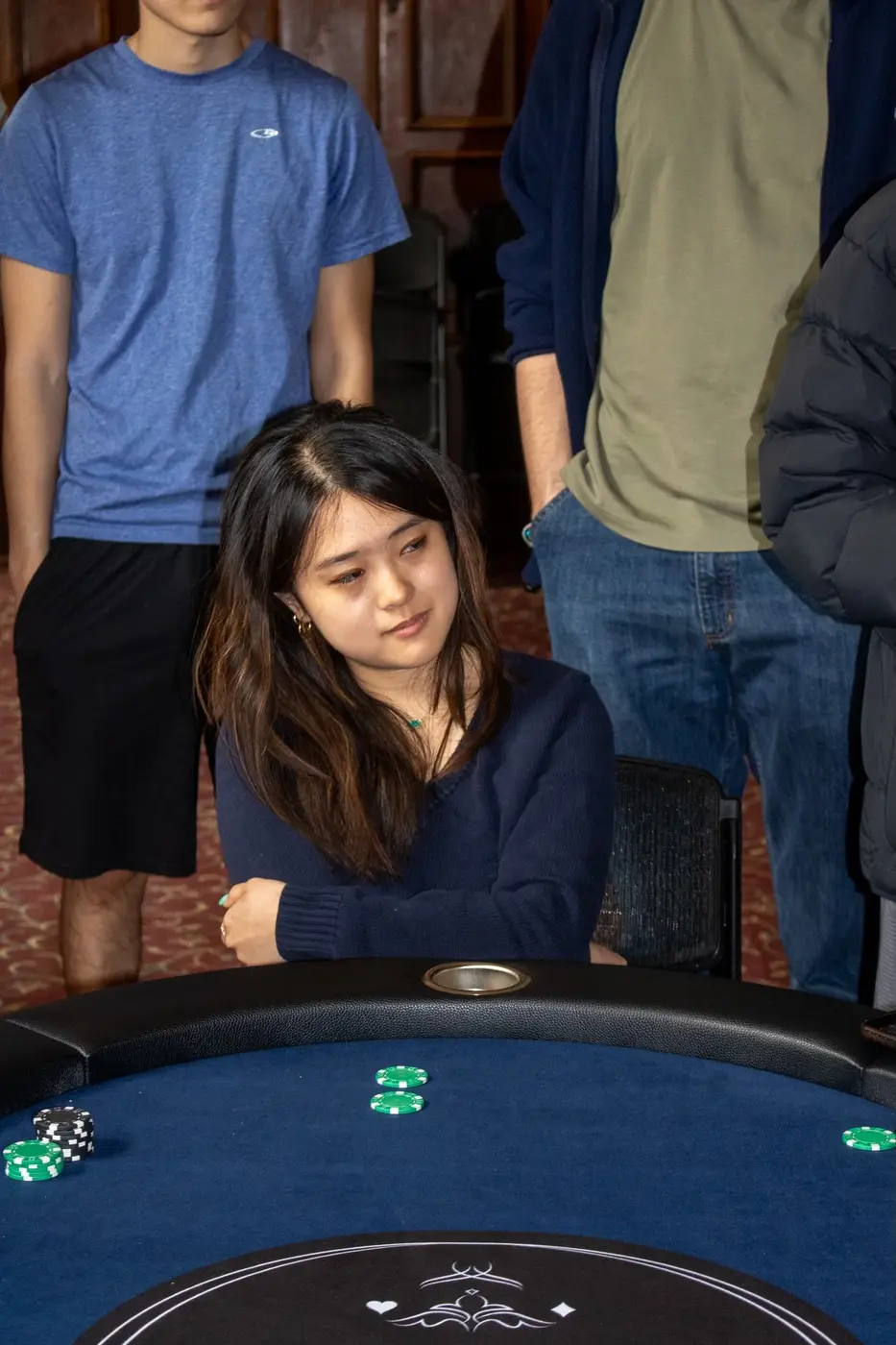 A member watches a hand from her seat, with onlookers behind her